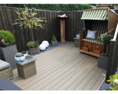 Espace jardin aménagé avec terrasse en bois, chaise de plage et plantations