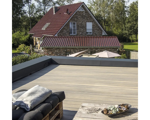 Grande terrasse en bois avec lames de terrasse et maison en arrière-plan