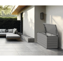 Gartenbox mit geöffnetem Deckel auf einer Terrasse neben Gartenmöbeln