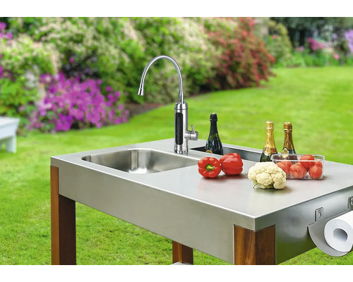 Cuisine extérieure avec évier, robinet, légumes, champagne et support pour essuie-tout dans le jardin