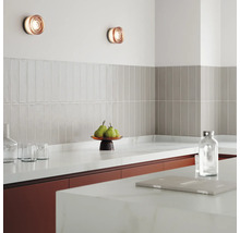 Scène de cuisine avec appliques murales, carrelage et ustensiles de cuisine sur le plan de travail.