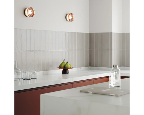 Scène de cuisine avec appliques murales, carrelage et ustensiles de cuisine sur le plan de travail.