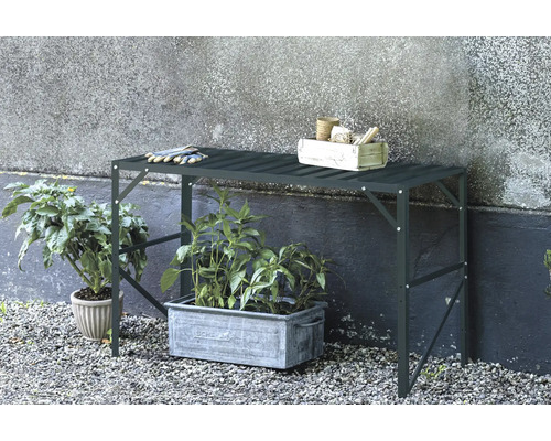 Table de jardin avec plantes, outils de jardinage et gants à l'extérieur