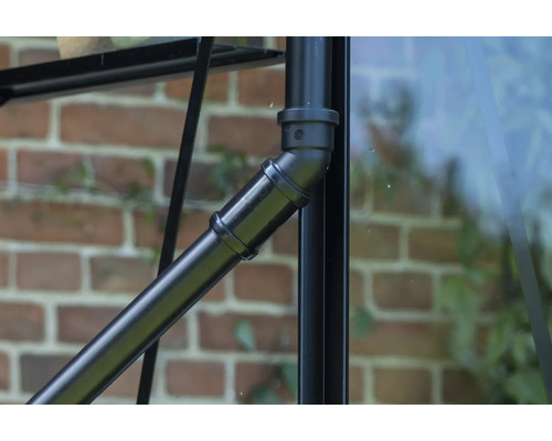 Gros plan d'un tube métallique noir avec des éléments de raccordement sur une serre.