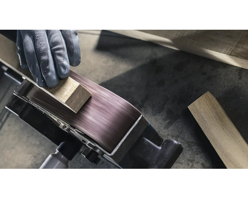 Gros plan d'une ponceuse à bande travaillant une pièce