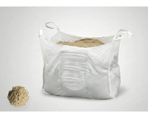 Grand Big Bag rempli de sable fin, à côté d'un petit tas de matériau.