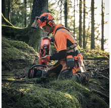 "Un bûcheron agenouillé dans les bois avec une tronçonneuse et un bidon de carburant 
