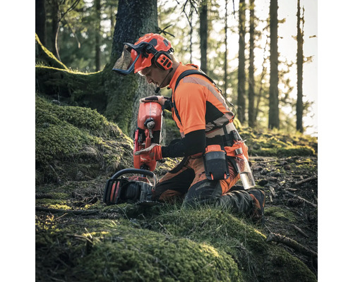 "Un bûcheron agenouillé dans les bois avec une tronçonneuse et un bidon de carburant 