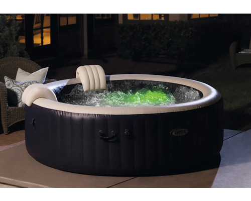 Jacuzzi gonflable avec appuie-tête et eau illuminée en couleur dans le jardin.