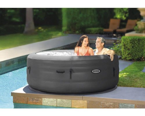 Aufblasbarer Whirlpool mit zwei Personen im Garten neben einem Pool. Intex Logo.