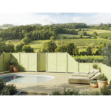 Terrasse en bois avec piscine ovale intégrée, clôture pare-vue en bois, bains de soleil en rotin et vue sur un paysage vallonné et boisé.