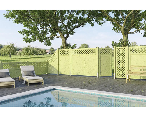 Grande terrasse avec piscine, platelage en bois sombre et clôture de jardin en bois vert clair munie de treillis décoratifs.