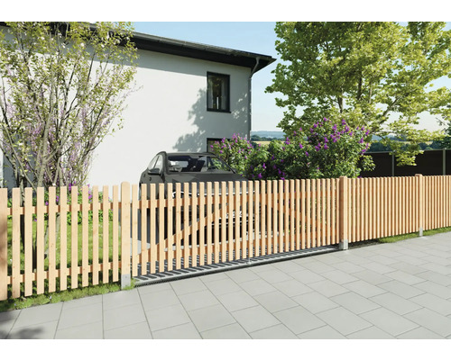 Moderner Lattenzaun aus Holz mit integriertem Schiebetor vor einem Wohnhaus und Garten. Senkrechte Holzlatten auf gepflastertem Boden.
