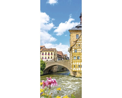 Vue sur l'ancien hôtel de ville de Bamberg avec un pont en arc de pierre sur la rivière et des maisons à colombages historiques.