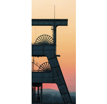 Silhouette d'un chevalement de mine avec deux molettes sur fond de ciel au coucher du soleil.