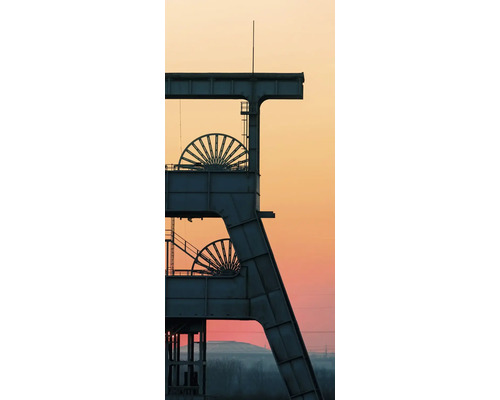 Silhouette d'un chevalement de mine avec deux molettes sur fond de ciel au coucher du soleil.