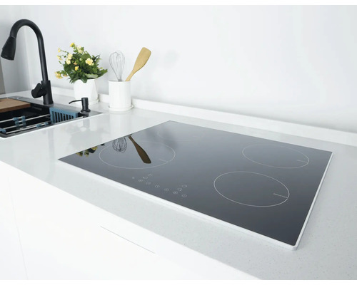 Plaque à induction avec quatre zones de cuisson dans une cuisine moderne et lumineuse sur un plan de travail blanc à côté de l'évier.