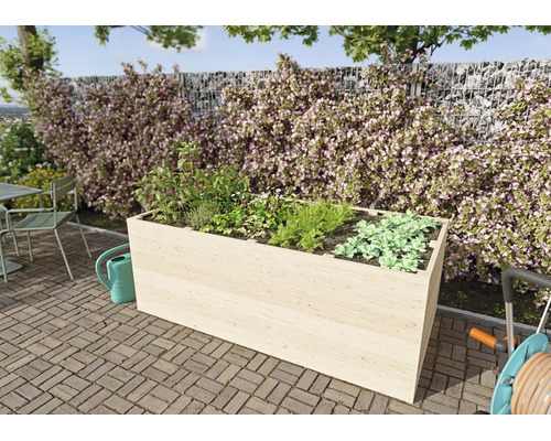 Rechteckiges Hochbeet aus hellem Holz mit Kräutern und Gemüse auf einer gepflasterten Terrasse vor einer bepflanzten Steinmauer.