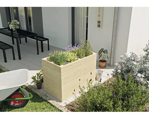 Rechteckiges Hochbeet aus hellem Holz mit horizontaler Lattung, bepflanzt mit Kräutern auf einer modernen Terrasse neben einer Sitzgruppe.
