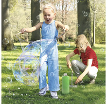 Deux enfants jouent dans le parc avec un jeu de bulles et créent de grosses bulles de savon.
