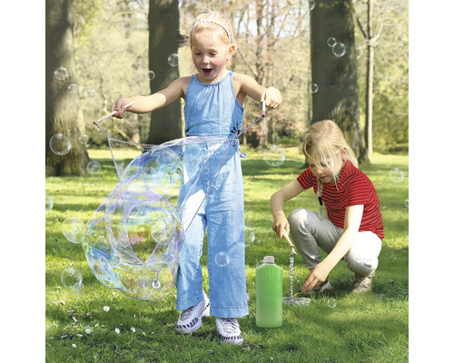 Deux enfants jouent dans le parc avec un jeu de bulles et créent de grosses bulles de savon.