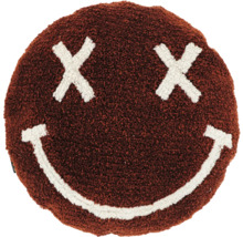 Rundes braunes Dekokissen aus flauschigem Stoff mit einem weißen Smiley-Gesicht aus Kreuzen als Augen und einem lächelnden Mund.