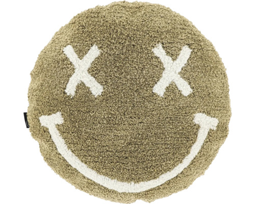 Rundes, flauschiges Kissen in Sandfarben mit einem Smiley-Gesicht aus zwei Kreuzen als Augen und einem lächelnden Mund.