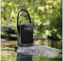 Station de charge portable avec poignée et affichage numérique sur un rocher dans un ruisseau devant une forêt floue.