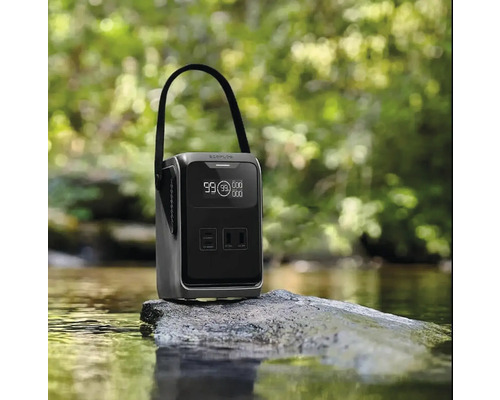 Station de charge portable avec poignée et affichage numérique sur un rocher dans un ruisseau devant une forêt floue.