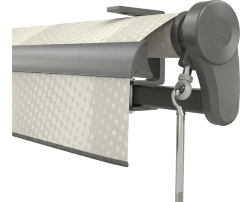 Gros plan d'un mécanisme de store manuel avec un anneau pour manivelle, un support latéral et un tissu à motifs.