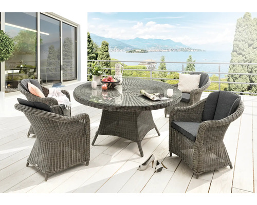 Salon de jardin en résine tressée avec table ronde en verre et quatre fauteuils, coussins inclus, sur une terrasse lumineuse.