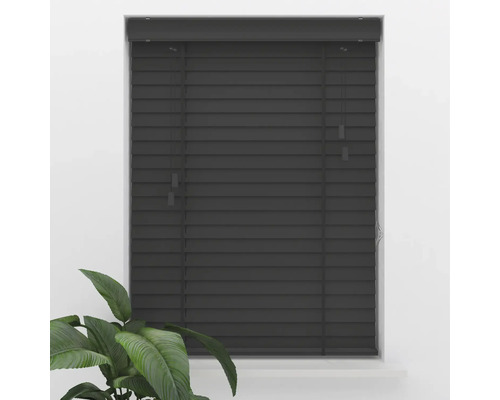 Store vénitien en bois gris foncé avec de larges lamelles, monté dans un cadre de fenêtre, avec une plante verte au premier plan.