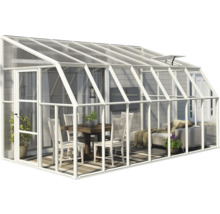 Anlehngewächshaus mit weißem Aluminiumrahmen und Glaswänden, eingerichtet mit Esstisch, Stühlen und Sofa als heller Wohnraum im Freien.