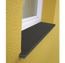 Appui de fenêtre extérieur en pierre naturelle foncée sur une façade jaune sous une fenêtre blanche.