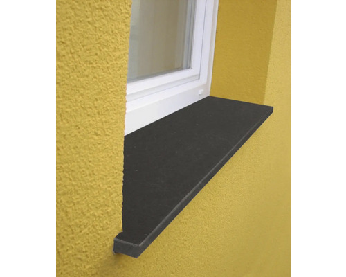 Appui de fenêtre extérieur en pierre naturelle anthracite, monté on une façade sous un cadre de fenêtre blanc.