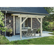 Terrassenüberdachung aus hellem Holz an einer Klinkerwand, darunter eine Sitzgruppe mit Tisch und vier Stühlen auf einer gepflasterten Terrasse.