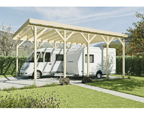 Carport en bois pour camping-cars et caravanes avec toit plat dans un jardin devant des haies et des montagnes.