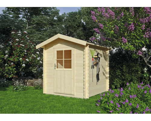 Petit abri de jardin en bois clair de style chalet avec toit à deux pans et porte simple vitrée dans un jardin lumineux avec des lilas en fleurs.
