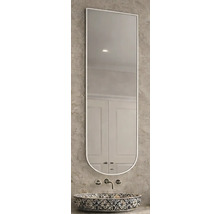 Schmaler Wandspiegel mit gerader Oberkante und abgerundeter Unterkante über einem gemusterten Waschbecken an einer strukturierten Wand.