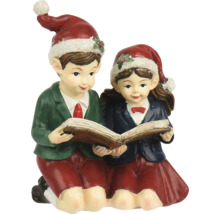 Figurine de Noël garçon et fille lisant un livre ensemble, portant tous deux des bonnets de Noël.