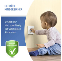 Ein Kleinkind greift nach einer Wandsteckdose, die mit einem geprüften Kinderschutz versehen ist.