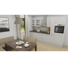 Cuisine intégrée moderne blanche avec électroménager et coin repas avec table en bois et banc rembourré.