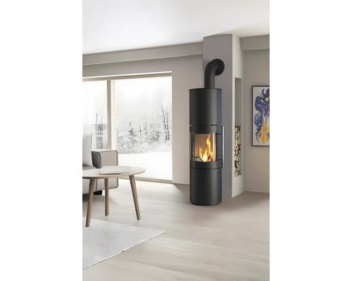 Poêle à bois rond et moderne dans un salon lumineux avec une grande fenêtre donnant sur un paysage enneigé.