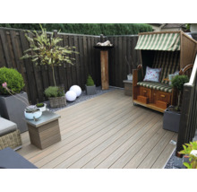 Terrasse moderne avec des lames en bois composite, une clôture en bois, une corbeille de plage et divers pots de fleurs.