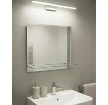 Salle de bain moderne avec miroir rectangulaire, tablette en verre, éclairage mural et lavabo en céramique avec robinet chromé.