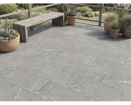 Terrassenplatten in Steinoptik mit grauer Marmorierung auf einer Terrasse mit Holzbank und Pflanzkübeln im Außenbereich.