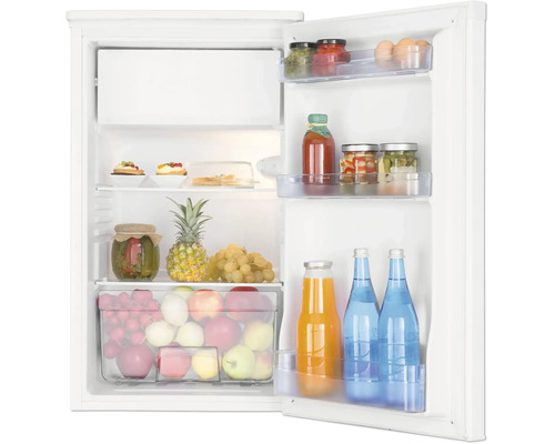 Réfrigérateur blanc ouvert avec compartiment congélateur, rempli de fruits, légumes, bocaux et bouteilles sur des clayettes en verre.