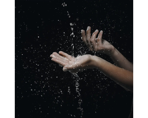 Nahaufnahme von Händen, die einen Wasserstrahl auffangen, mit zahlreichen Wassertropfen und Spritzern.