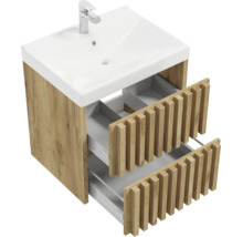 Meuble sous-vasque aspect bois avec deux tiroirs ouverts au design à lamelles et vasque blanche avec robinet.