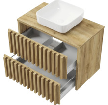 Meuble sous-vasque aspect chêne avec deux tiroirs ouverts à façades à lattes et une vasque à poser blanche.